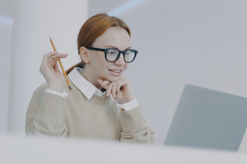 Female student is reading on PC. Smiling girl is browsing information and doing research.